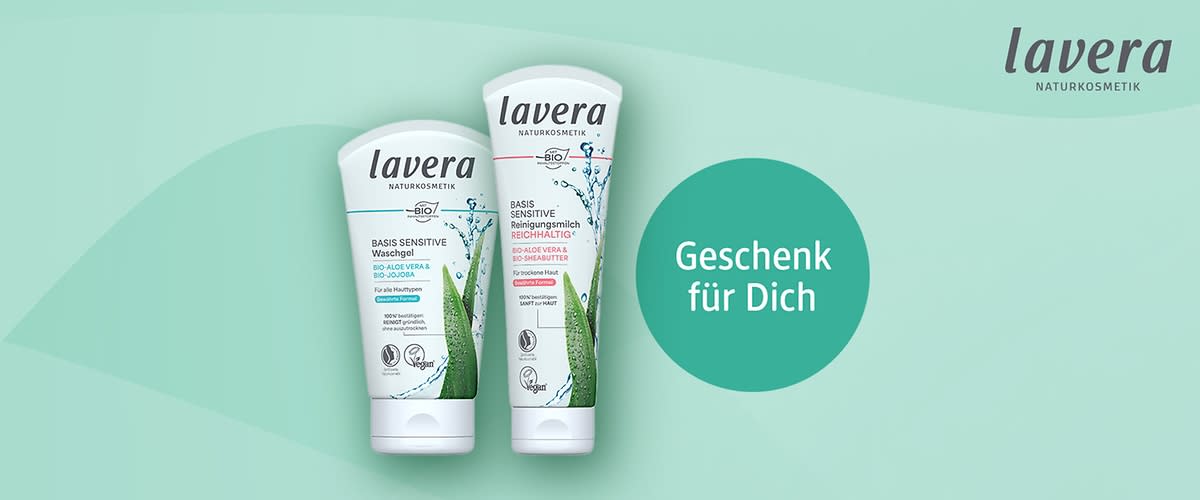 Zwei Lavera Naturkosmetik-Tuben nebeneinander, links „Basis Sensitive Waschgel“, rechts „Basis Sensitive Reinigungsmilch“, rechts daneben grüner Kreis mit weißer Aufschrift „Geschenk für Dich“, oben rechts Lavera-Logo
