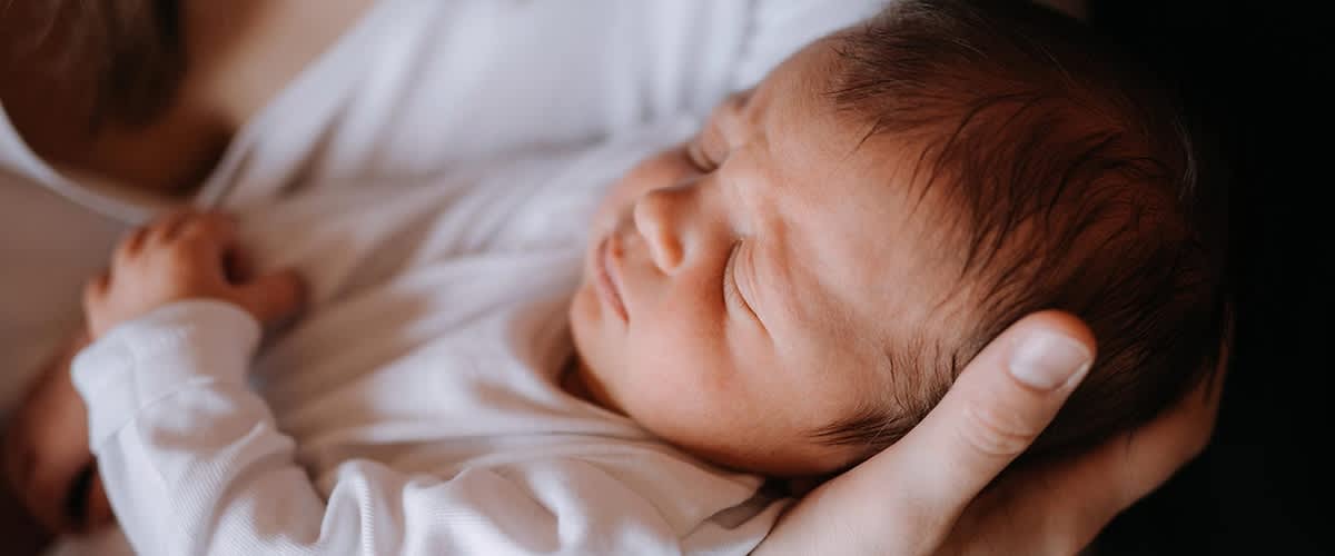 Mama hÀlt ihr Baby im Arm