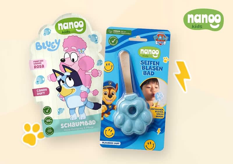 zwei Nanog Kids Bath-Artikel: links eine stehende, pastellrosa-weiße Schaumbad-Verpackung mit Cartoon-Hunden und Aufschrift „Schaumbad“ sowie Hinweis „Candy Duft“, rechts eine blaue Pfoten-Seifenblasenform in Blisterverpackung mit Aufschrift „Seifenblasen Bad“ und lachenden Smileys