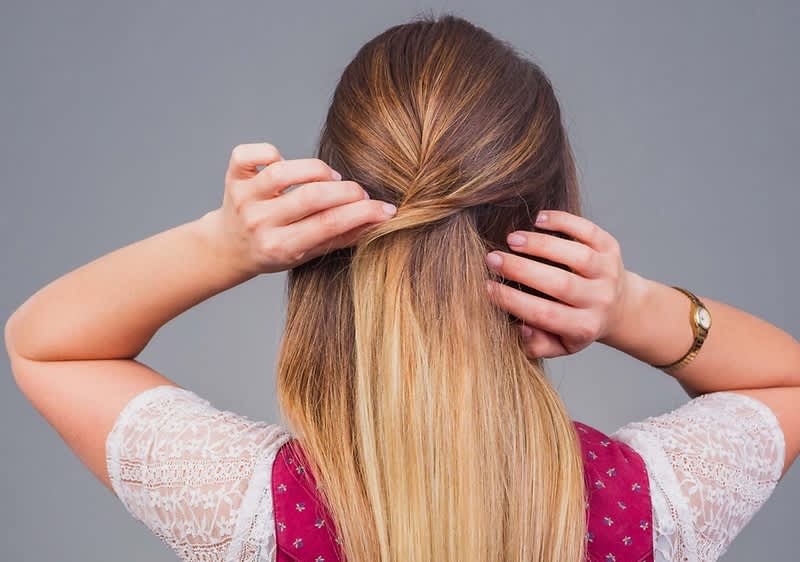 Frau bindet ihre Haare zusammen