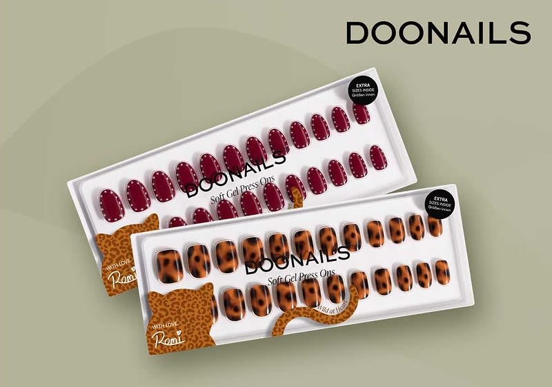 Zwei Packungen Doonails Soft Gel Press Ons künstliche Fingernägel, oben dunkelrote Nägel mit goldenen Punktakzenten, unten Leopardenmuster in Braun- und Schwarztönen, Verpackungen mit durchsichtigem Fenster und Doonails-Logo