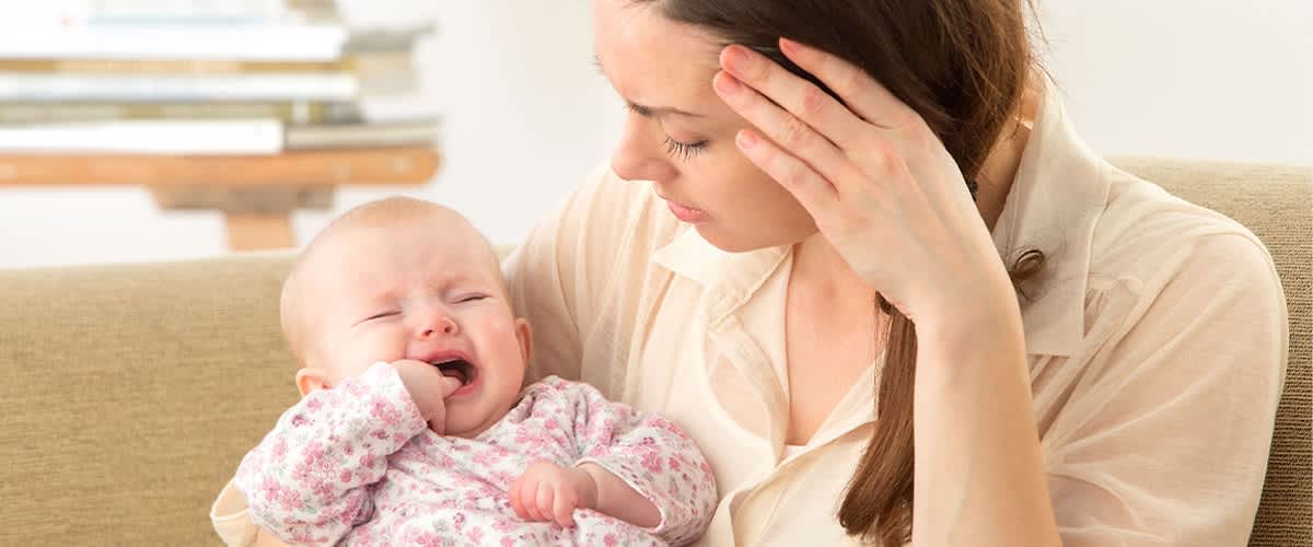 Angespannte Frau hat schreiendes Baby auf dem Arm
