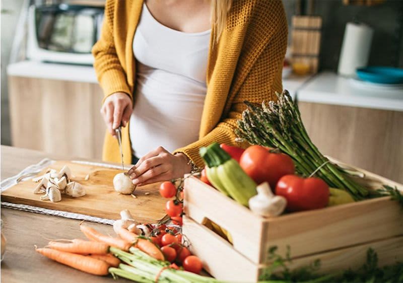 Ernährung in der Schwangerschaft: Frau schneidet Gemüse