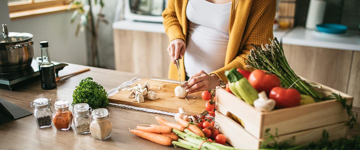 Ernährung in der Schwangerschaft: Frau schneidet Gemüse