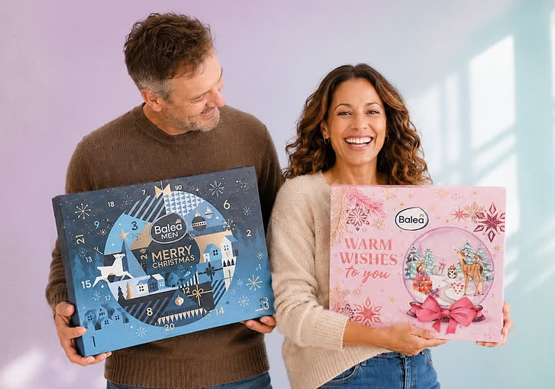 Zwei Produktverpackungen vor einem rosa Hintergrund, links eine große Box mit der Aufschrift Beauty Full Christmas und trend IT UP in einem winterlichen Stadtbild mit Schneeflocken und einem Schaufenster mit Kosmetikprodukten, rechts eine kleinere Box mit der Aufschrift CUPPER TEA ADVENT CALENDAR und 24 CUPS TEAS & INFUSIONS BIO in einem festlichen Design mit einem grünen Dach und roten Wänden, beide Verpackungen sind von einer leuchtenden Lichterkette umgeben. Bild mithilfe von KI erstellt
