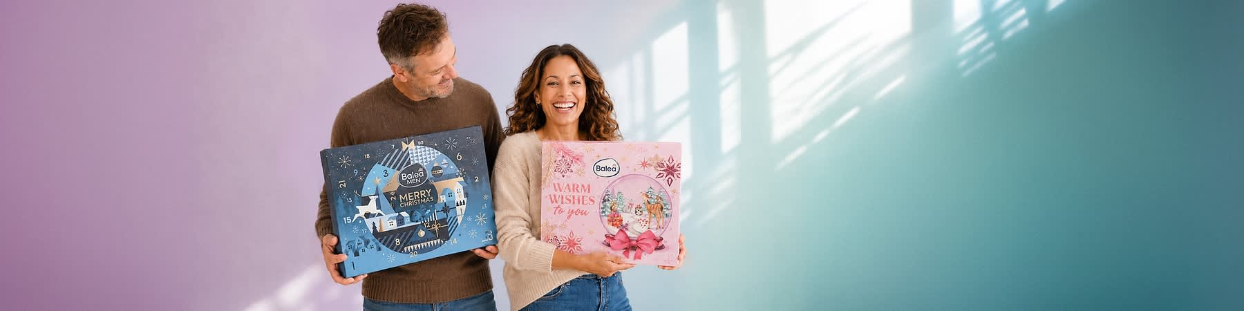 Zwei Produktverpackungen vor einem rosa Hintergrund, links eine große Box mit der Aufschrift Beauty Full Christmas und trend IT UP in einem winterlichen Stadtbild mit Schneeflocken und einem Schaufenster mit Kosmetikprodukten, rechts eine kleinere Box mit der Aufschrift CUPPER TEA ADVENT CALENDAR und 24 CUPS TEAS & INFUSIONS BIO in einem festlichen Design mit einem grünen Dach und roten Wänden, beide Verpackungen sind von einer leuchtenden Lichterkette umgeben. Bild mithilfe von KI erstellt