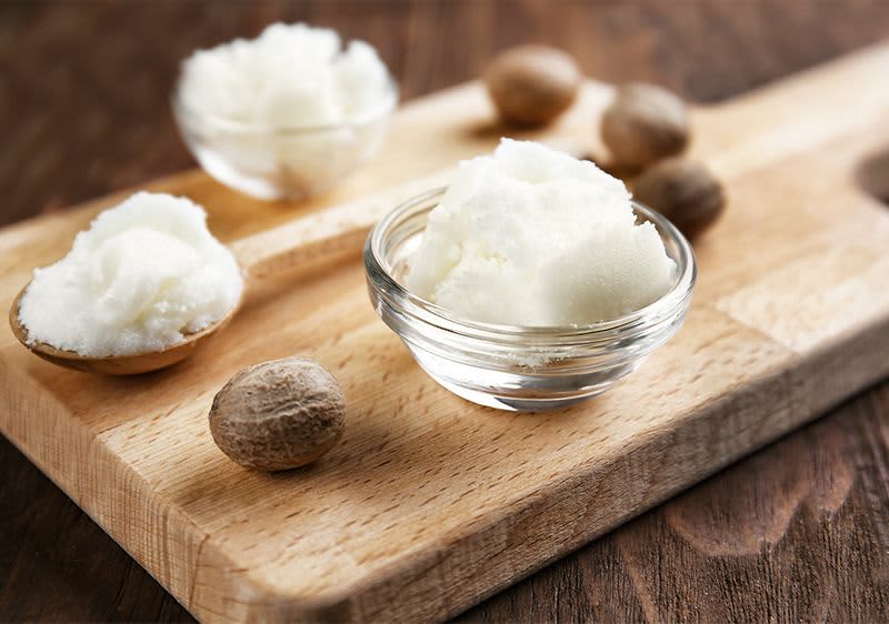Schale mit Sheabutter auf Holzbrett