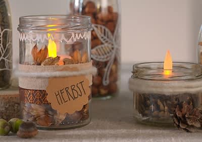 Dekorierte Gläser mit Herbstmotiven und Kerzenlicht