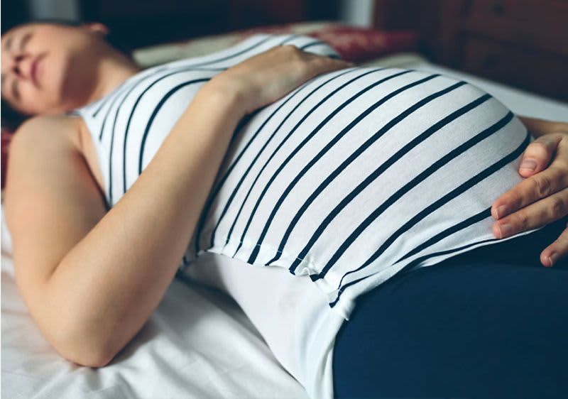 Frau liegt auf Rücken: Entspannungsübungen während der Schwangerschaft