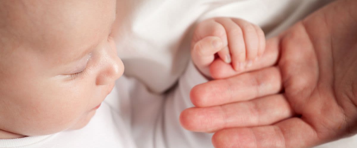 U3-Untersuchung: Babyhand umfasst den Finger eines Erwachsenen