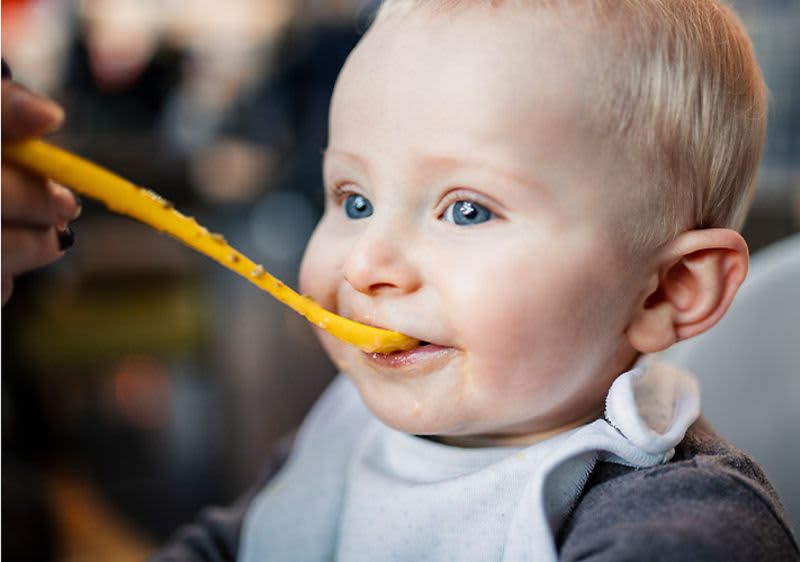 Baby bekommt Brei mit einem Löffel