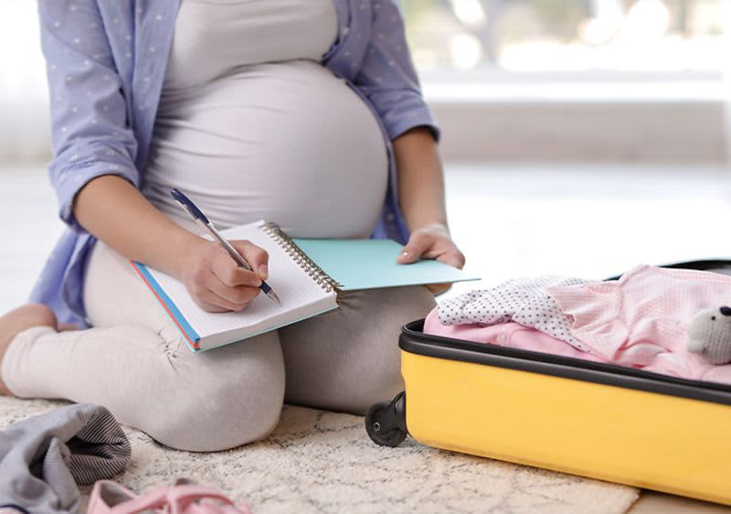 Schwangere Frau schreibt etwas in ein Notizbuch