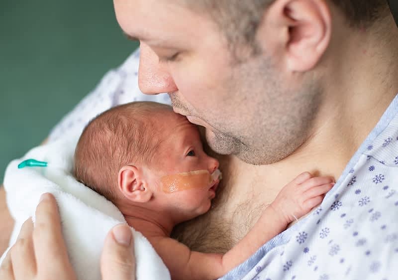 Papa mit Frühchen auf dem Arm