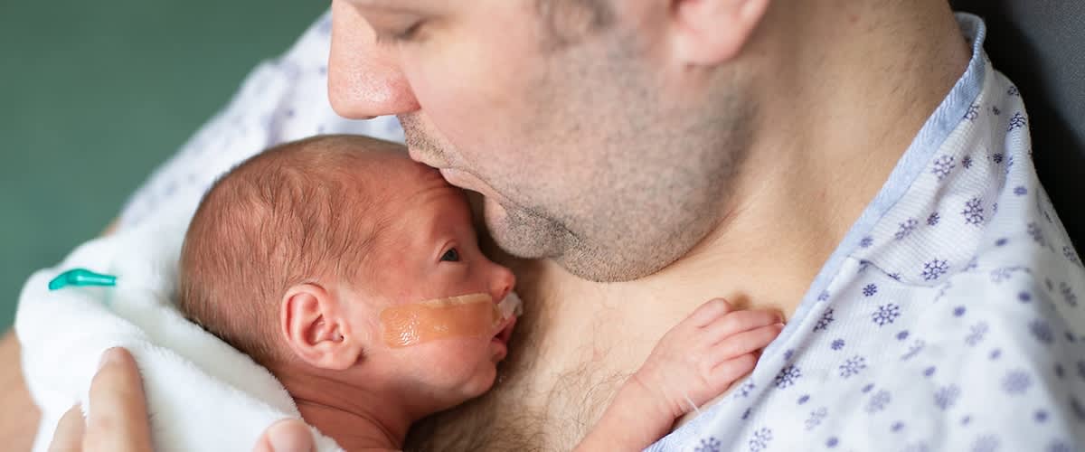 Papa mit Frühchen auf dem Arm