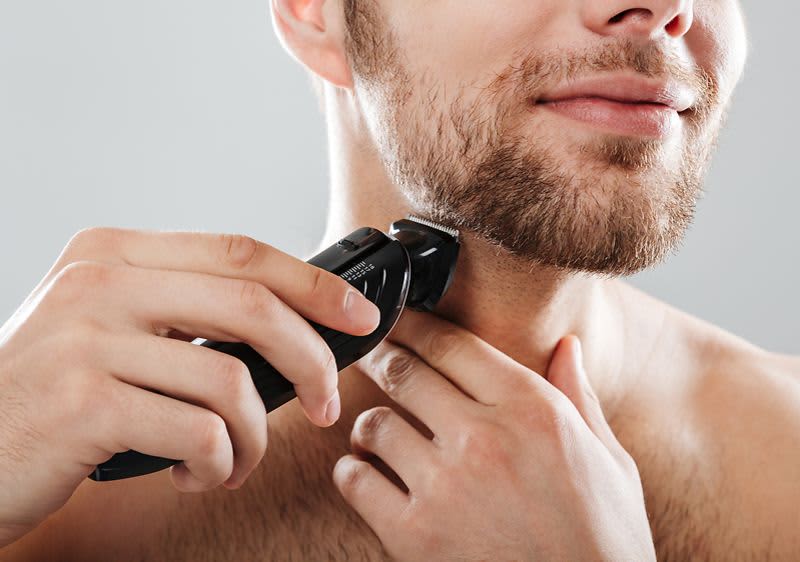 Mann stutzt seinen Bart.