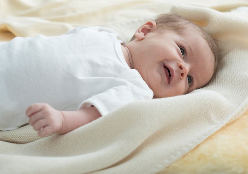 Baby liegt auf kuscheligen Decken