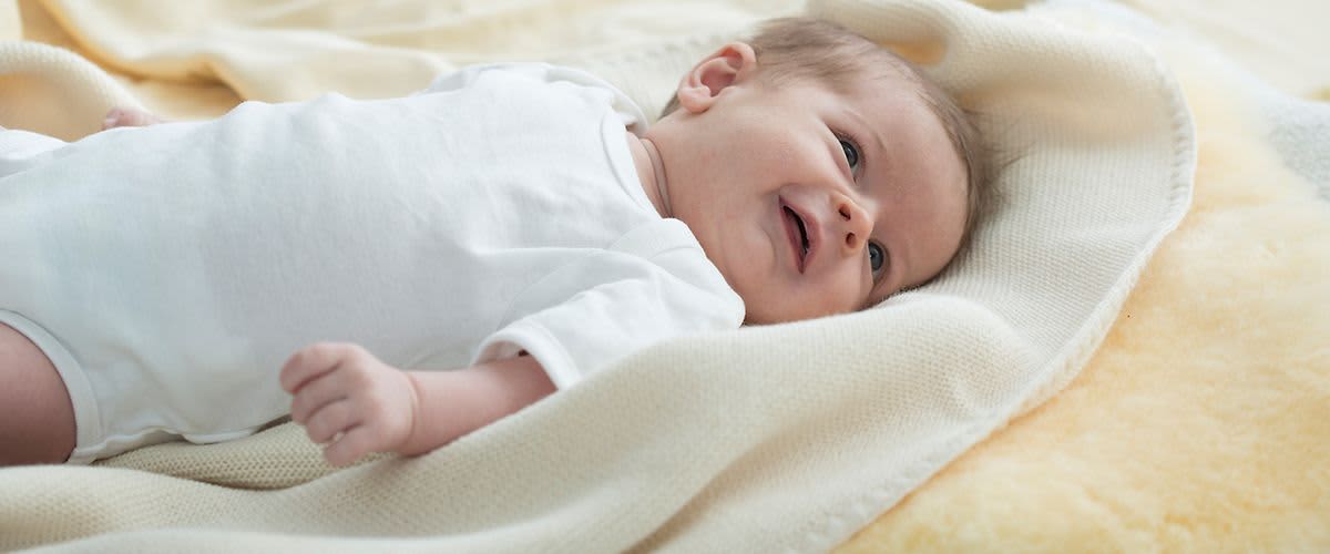 Baby liegt auf kuscheligen Decken