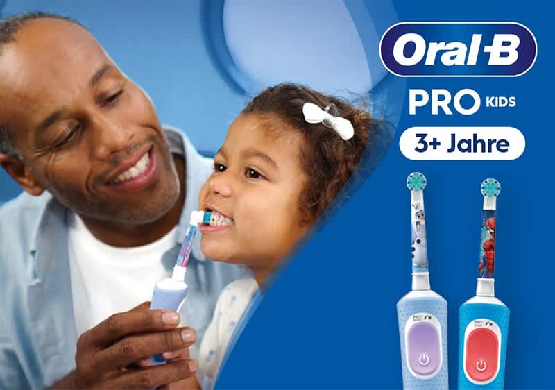 Werbungspackung für Oral‑B Pro Kids elektrische Kinderzahnbürsten ab 3 Jahren, rechts zwei bunte Bürstenkörper mit blauem und rotem Farbakzent und kindlichen Motivaufsätzen, oben rechts Oral‑B Logo und Schriftzug „PRO KIDS 3+ Jahre“, links unscharfe Aufnahme zweier Personen, eine hält eine elektrische Zahnbürste in der Hand