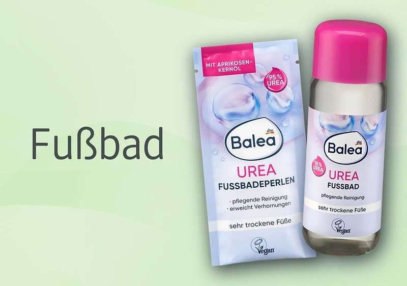 Grüne Werbegrafik mit zwei Balea-Produkten für ein Fußbad: links eine pastellblaue Packung „Balea Urea Fußbadeperlen“ mit Hinweis „mit Aprikosenkernöl“ und „sehr trockene Füße“, rechts eine Flasche „Balea Urea Fußbad“ mit pinker Kappe und gleicher Kennzeichnung; links daneben großes Wort „Fußbad”