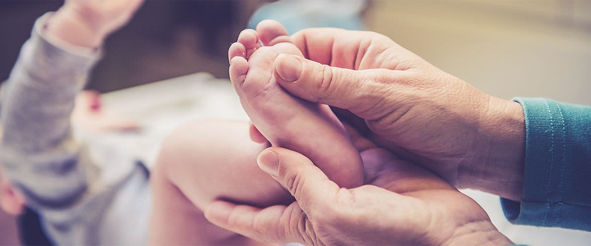 Ein Baby bekommt den Fuß massiert.