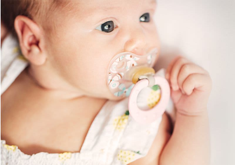 Baby mit Schnuller im Mund.