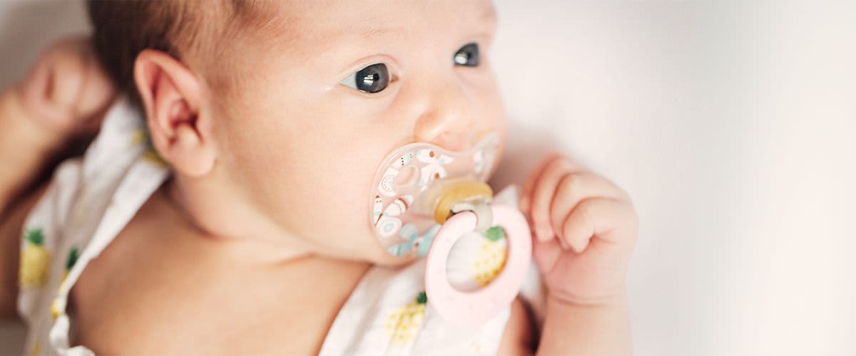 Baby mit Schnuller im Mund.