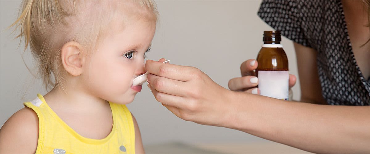 Kind bekommt einen Löffel mit Medizin