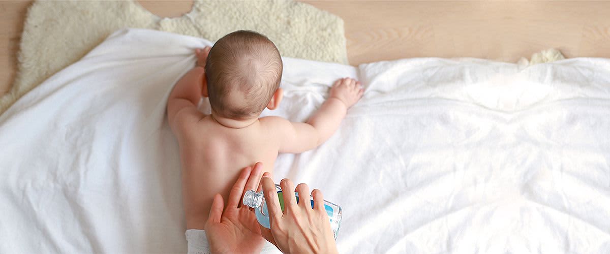 Baby bekommt Rücken eingecremt