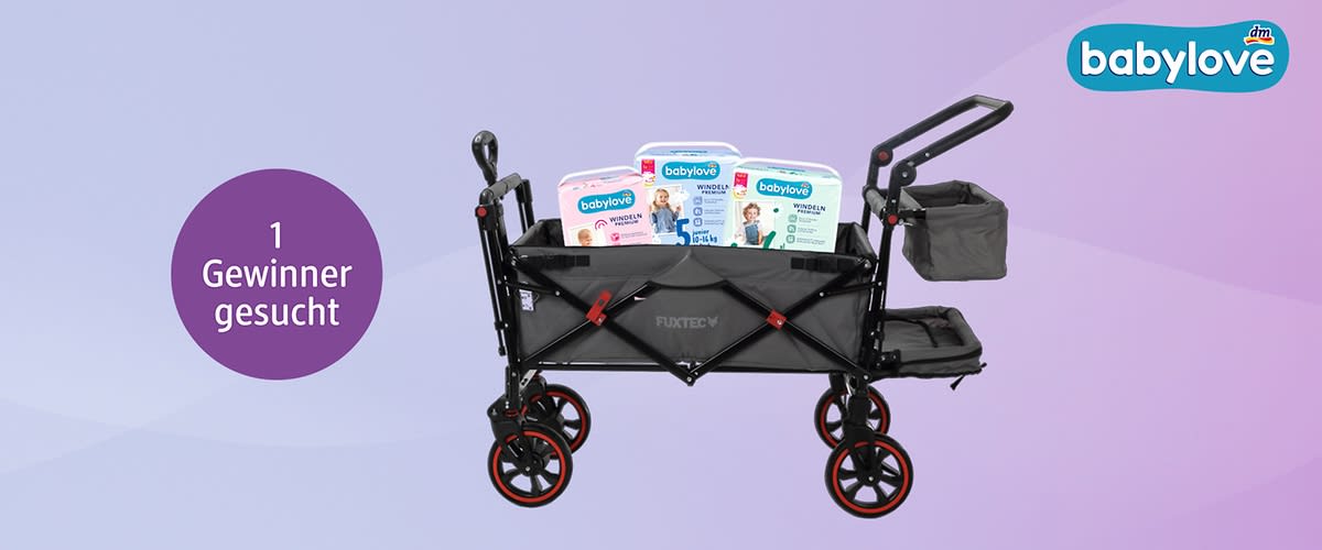 Ein schwarzer Bollerwagen mit roten Rädern enthält drei Packungen Babylove-Windeln. Oben rechts ist das Babylove-Logo zu sehen. Links im Bild steht in einem lila Kreis der Text „1 Gewinner gesucht“