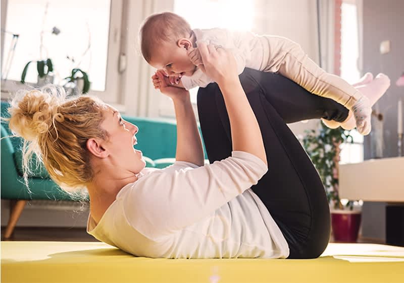 Frau bei Mama-Baby-Yoga mit ihrem Kind 