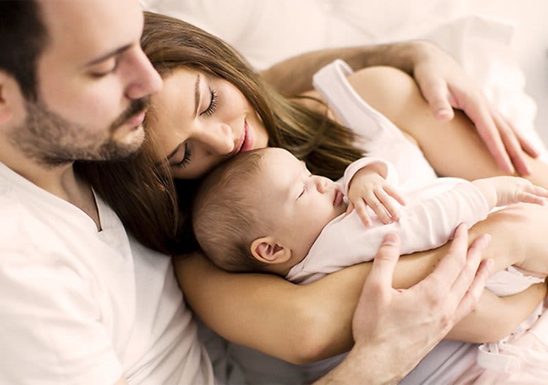 Vater, Mutter und Baby kuscheln