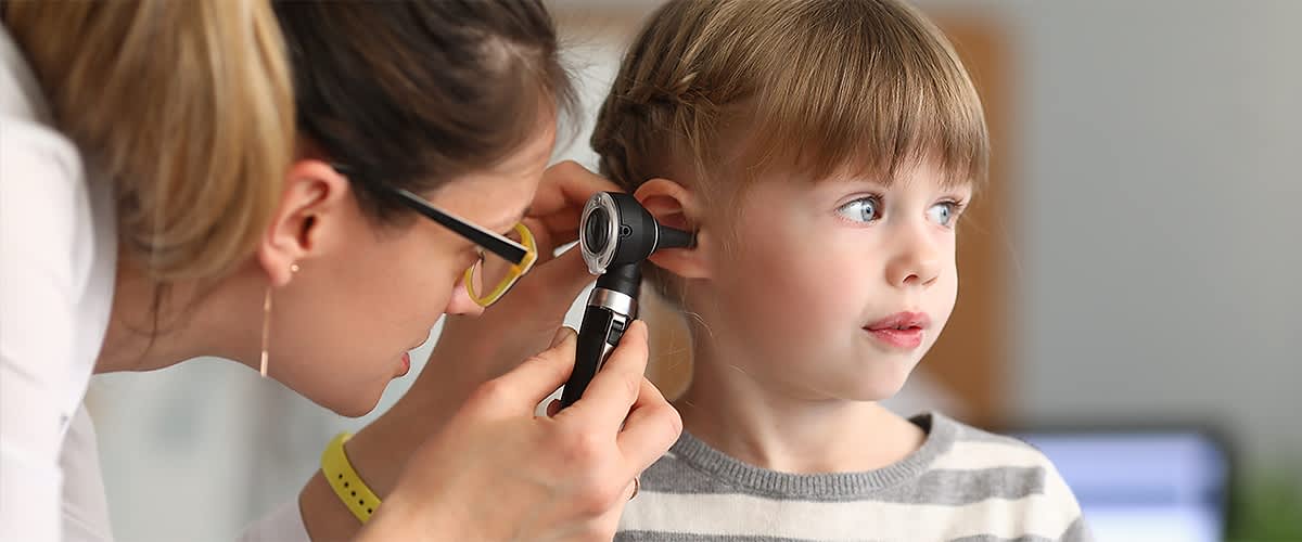 Kinderkrankengeld: Ärztin schaut Kind ins Ohr