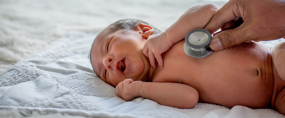 Baby wird mit einem Stethoskop abgehört