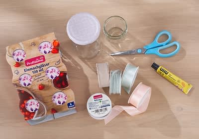 Benötigte Materialien abgebildet: Einmachgläser, Geschenkbänder, Kordel, Schere und Kleber