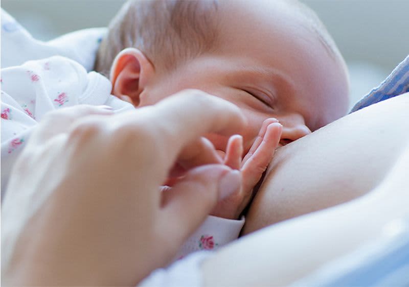 Baby liegt an der Brust und wird gestillt