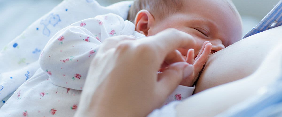 Baby liegt an der Brust und wird gestillt