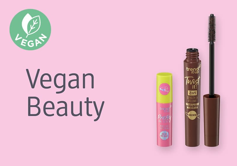 Auf rosa Hintergrund links ein grüner Kreis mit weißem Blatt und dem Schriftzug „VEGAN“, daneben der Text „Vegan Beauty“ in dunkelgrauer Schrift, rechts zwei Mascara-Produkte: eine kurze pink-grüne Tube mit Aufkleber und eine geöffnete braune Mascara mit aufgesetzter Bürste und der Aufschrift „trend IT UP Twist it! 2in1“