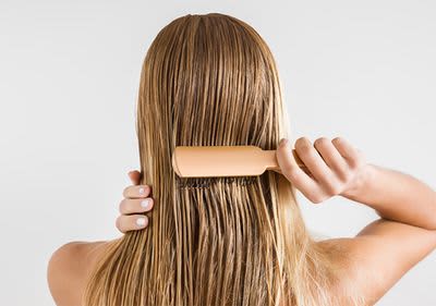 Frau bürstet sich das nasse Haar.