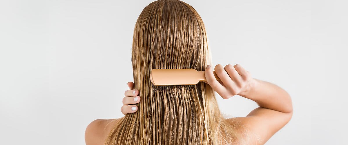 Frau bürstet sich das nasse Haar.