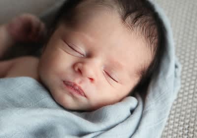 Schlafendes Neugeborenes in ein Tuch gehüllt