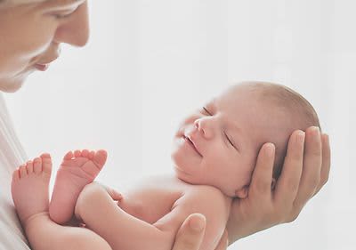 Neugeborenes Baby liegt in den Händen einer Frau