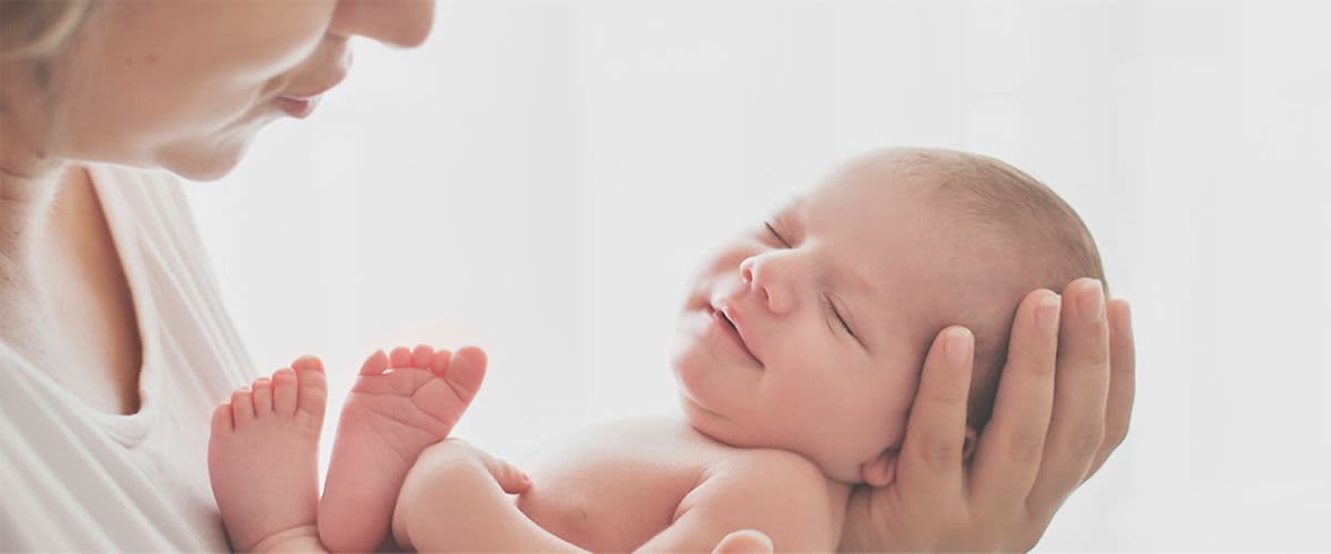 Neugeborenes Baby liegt in den Händen einer Frau