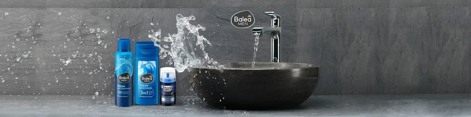 Drei blaue Balea Men Pflegeprodukte nebeneinander: links Antitranspirant-Spray mit Aufschrift „FRESH 48H ANTI-TRANSPIRANT“, Mitte Duschgel-Flasche mit Aufschrift „FRESH DUSCHGEL 3in1“, rechts kleine Pump-Flasche mit Aufschrift „FRESH“ vor spritzendem Wasser und dunkler Schale, oben rechts Balea Men Logo