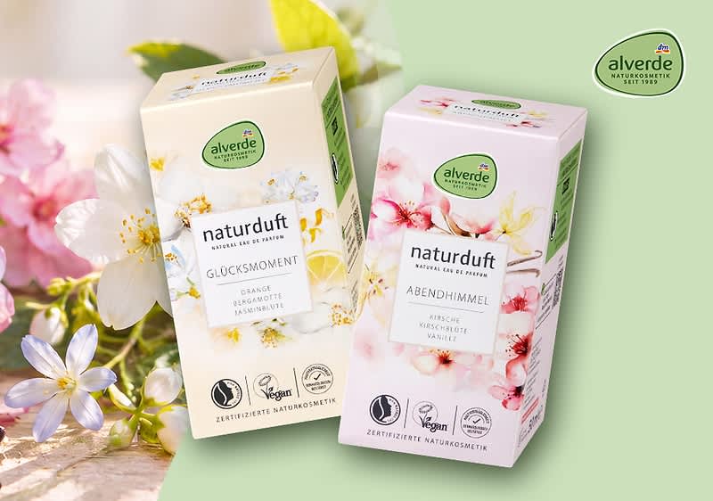 Drei Packungen Alverde Naturduft auf hellem Hintergrund, umgeben von Eukalyptusblättern. Links eine rote Packung mit der Aufschrift „Wunderwelt“, in der Mitte eine rosa Packung „Tagtraum“, rechts eine gelbe Packung „Sonnenseite“. Bild mithilfe von KI erstellt