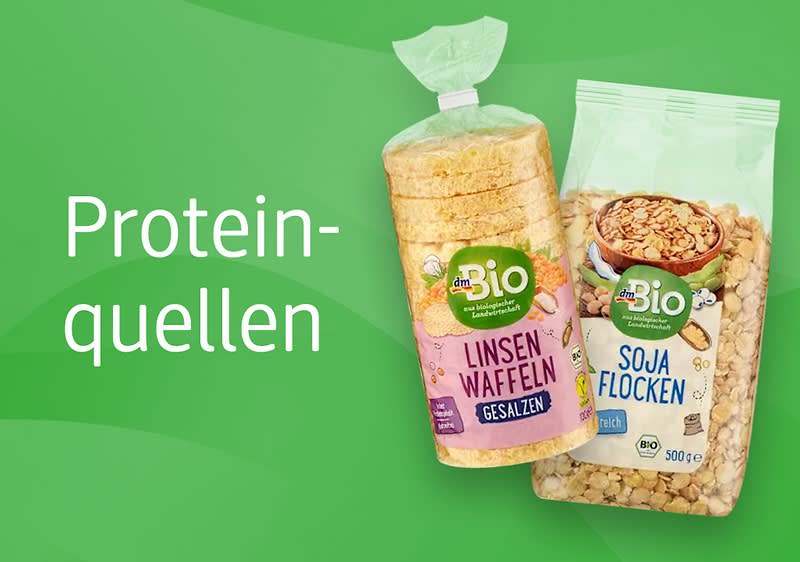 Zwei Bio-Produkte auf grünem Hintergrund: links eine transparente Plastikpackung mit gestapelten, runden Linsen-Waffeln mit violettem Etikett „Linsen Waffeln gesalzen“, rechts eine durchsichtige Tüte mit Sojaflocken und grünem Etikett „Soja Flocken“, links neben den Produkten weißer Schriftzug „Proteinquellen“