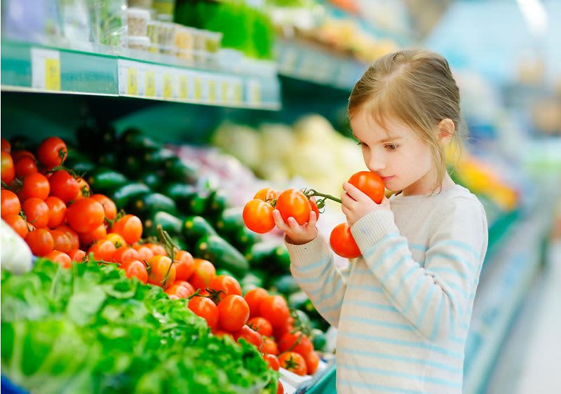 Mädchen riecht an frischen Tomaten
