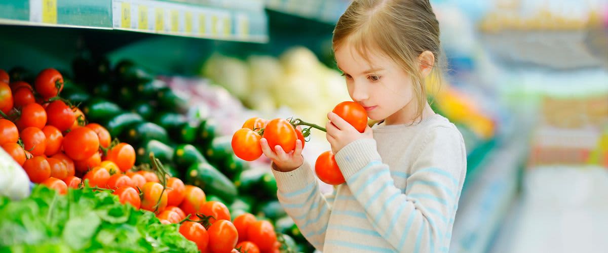 Mädchen riecht an frischen Tomaten