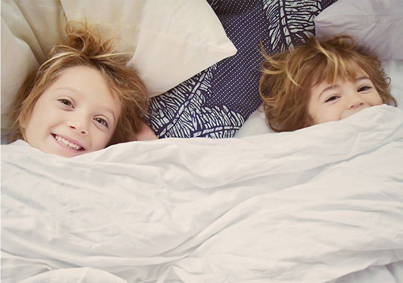 Zwei Kind liegen lachend im Bett