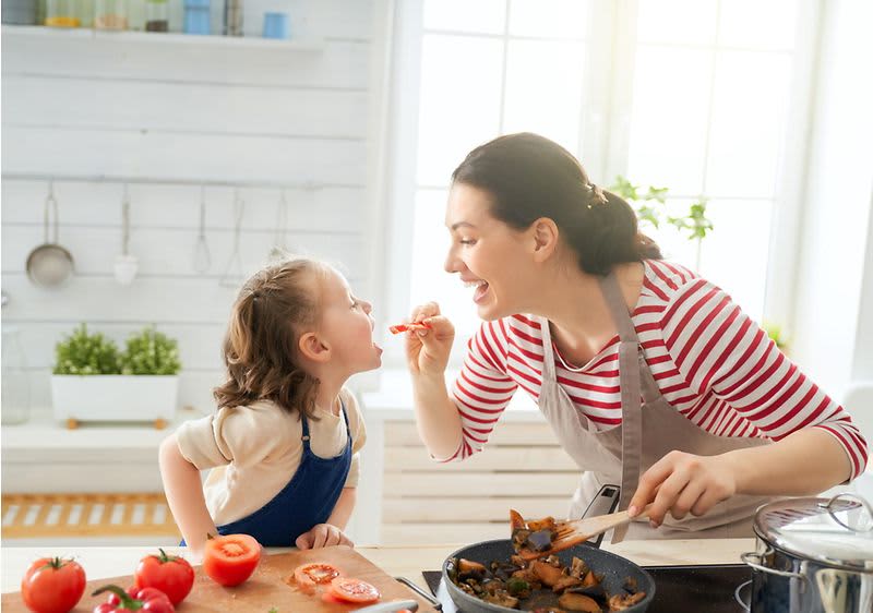Mutter lässt Kinder Gekochtes probieren