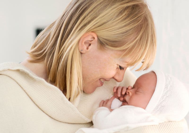 Mutter lächelt ihr Baby an und hält es im Arm